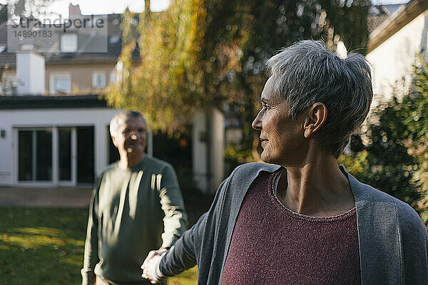 Liebenswertes älteres Ehepaar hält im Garten Händchen