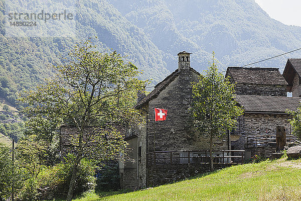 Schweiz  Tessin  Verzascatal  typisches Steinhaus mit Schweizer Nationalflagge