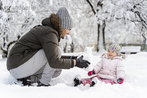 Glücklicher Vater spielt mit Tochter in Winterlandschaft