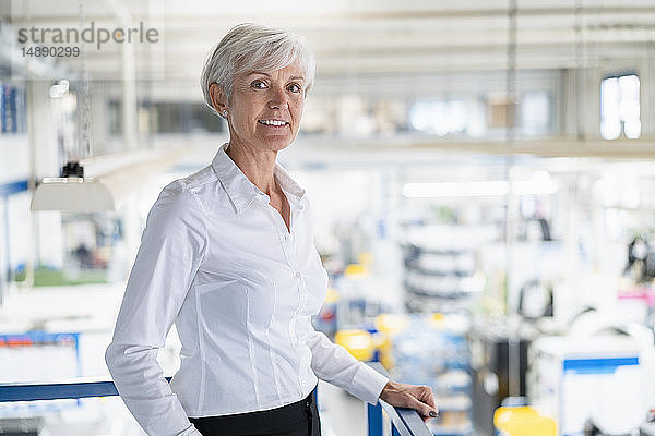 Porträt einer selbstbewussten älteren Geschäftsfrau im Obergeschoss einer Fabrik