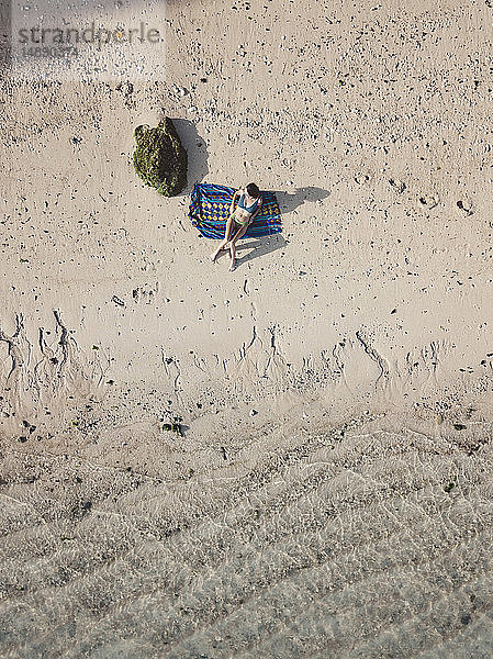 Frau entspannt sich auf einem Handtuch am Strand  Draufsicht