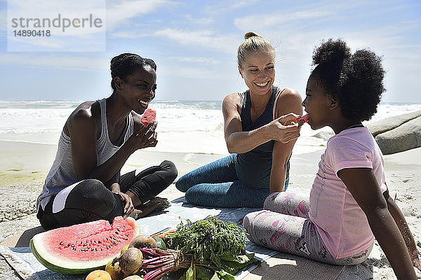 Mutter mit Tochter und Freundin beim Picknick am Strand