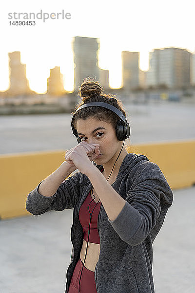 Sportliche junge Frau mit Kopfhörern beim Training  Boxen