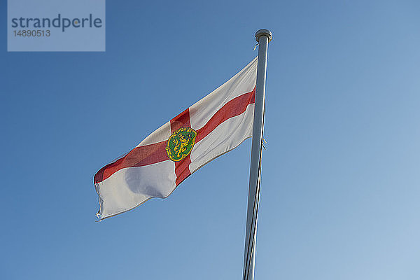 Vereinigtes Königreich  Kanalinseln  Alderney  Flagge von Alderney gegen blauen Himmel