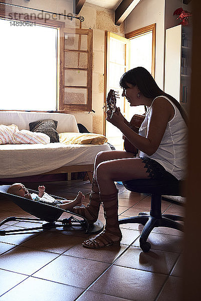 Mutter spielt Gitarre für kleinen Jungen zu Hause
