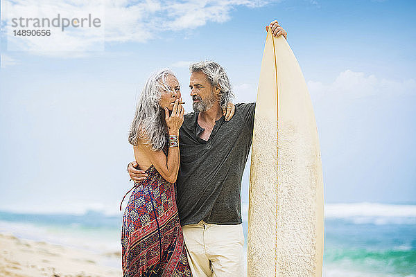 Älteres Hippie-Paar mit Surfbrett am Strand