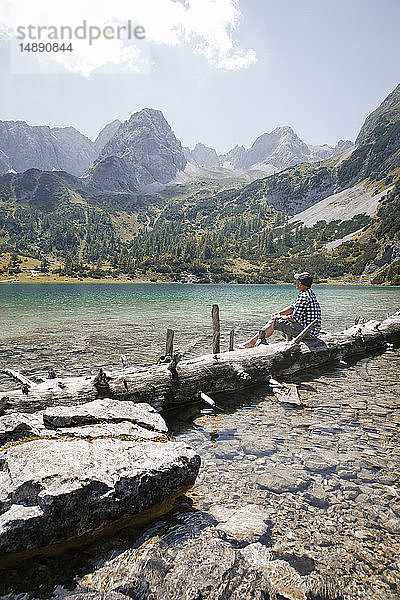 Österreich  Tirol  Mann auf Baumstamm am Seebensee sitzend