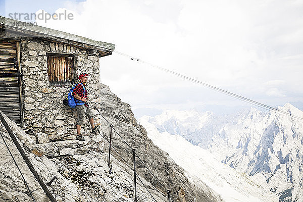 Österreich  Tirol  Mann auf einer Wanderung stehend auf einer Berghütte
