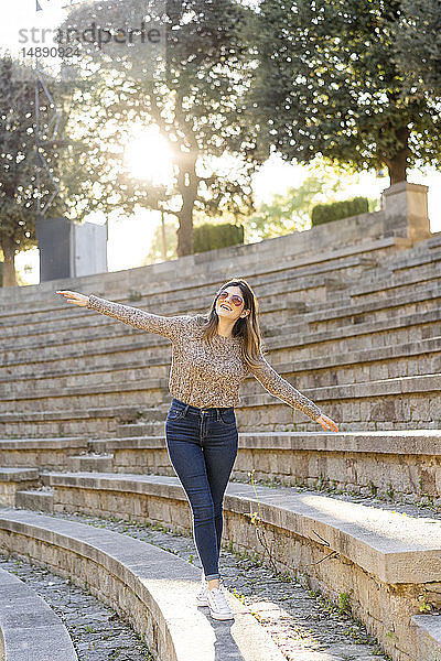Glückliche junge Frau balanciert auf einer Treppe im Freien