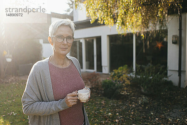 Porträt einer reifen Frau mit einer Tasse Kaffee im Garten