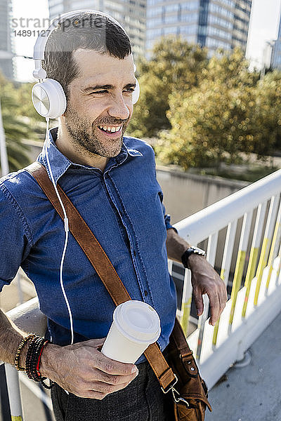 Porträt eines lächelnden Mannes mit Kaffee zum Musikhören mit Kopfhörern