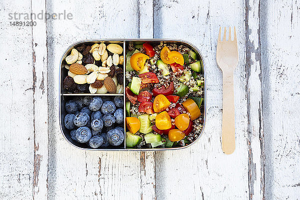 Lunchbox mit Quinoa-Salat mit Tomate und Gurke  blauen Beeren und Studentenfutter