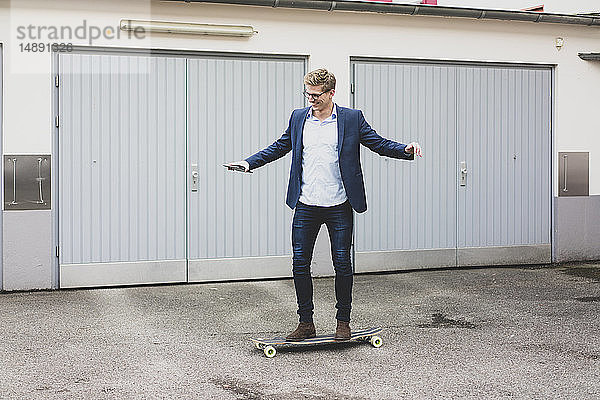 Junger Geschäftsmann fährt Skateboard am Garagentor