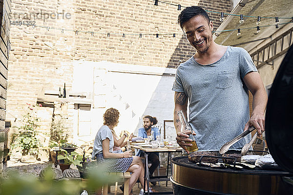 Junger Mann bereitet ein Fleisch für seine Freunde zu einer Ta-Barbecue-Party