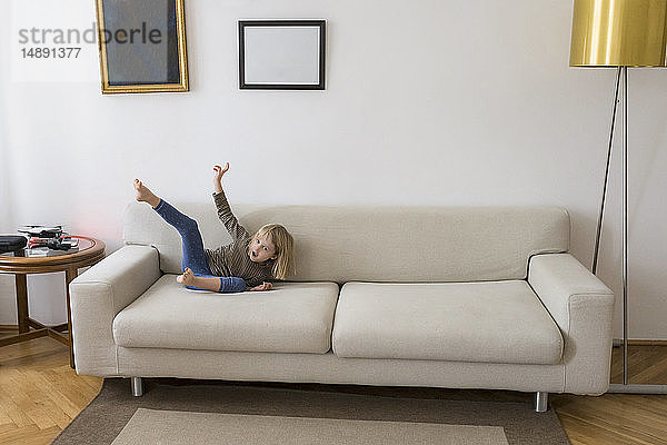 Kleines blondes Mädchen spielt zu Hause auf der Couch
