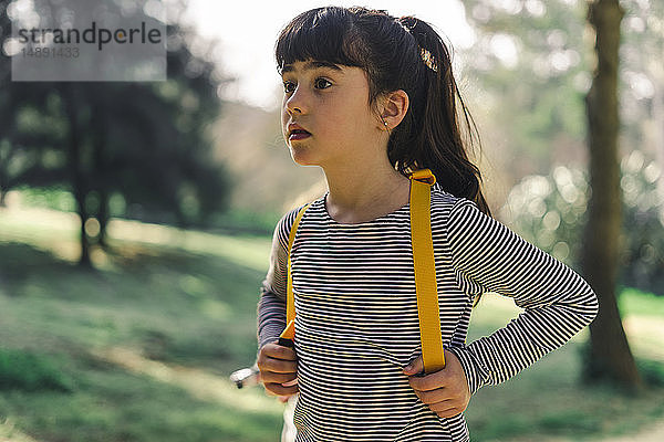 Porträt eines kleinen Mädchens mit Rucksack in Natur