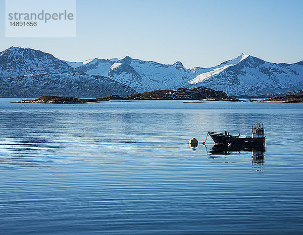 Fischerboot vor schneebedeckten Bergen in Tromso  Norwegen