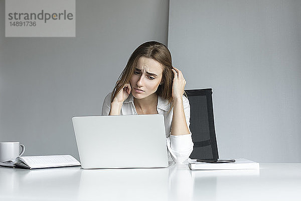 Frustrierte Geschäftsfrau bei der Arbeit am Laptop