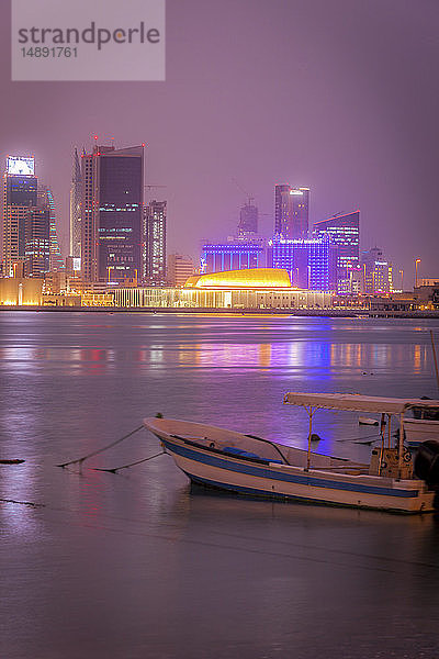 Vertäutes Motorboot vor der nächtlichen Skyline von Manama  Bahrain