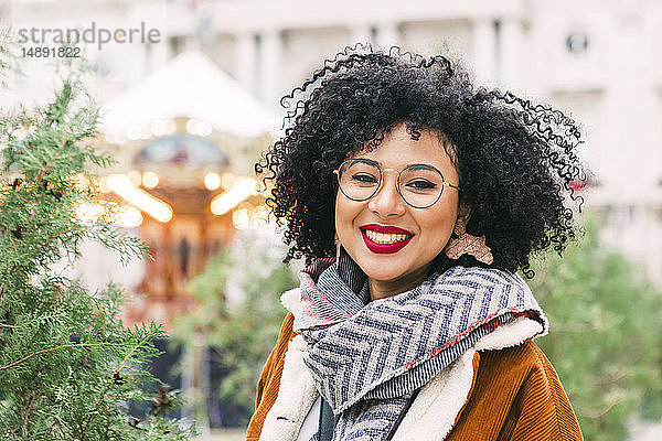 Porträt einer lächelnden jungen Frau mit Brille und rotem Lippenstift