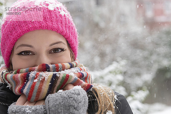 Porträt einer jungen Frau mit Wollmütze und Schal im Schnee