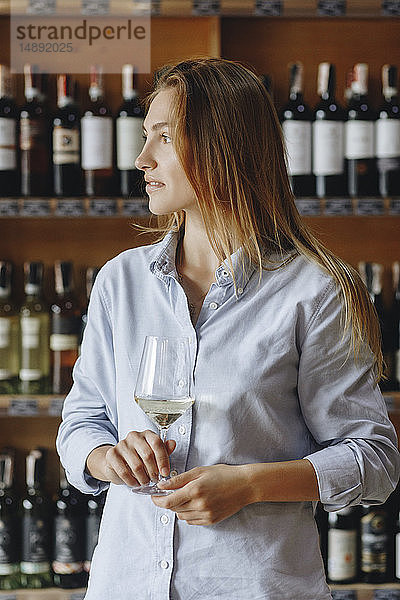 Junge Frau hält ein Glas Weißwein