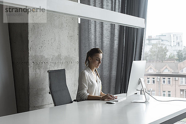 Junge Geschäftsfrau arbeitet an einem Desktop-Computer