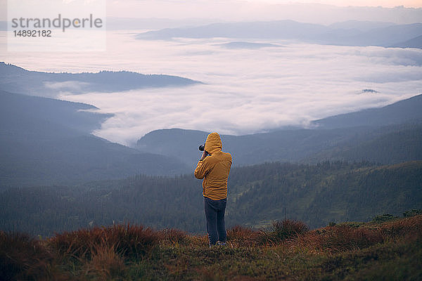 Mann in gelber Jacke beim Fotografieren in den Karpaten