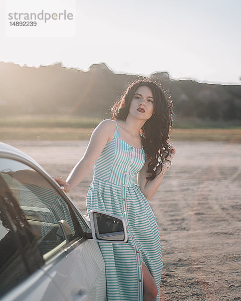 Junge Frau in gestreiftem Kleid an einem Auto