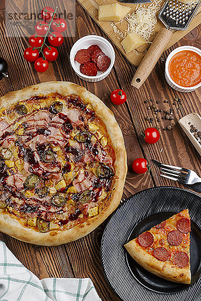 Pizza und Zutaten auf einem Holztisch
