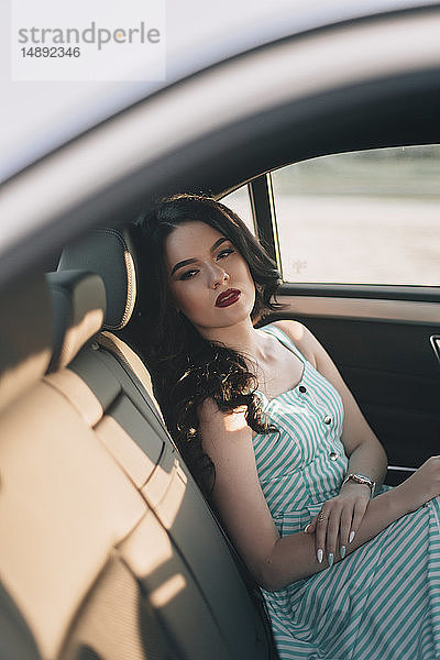 Junge Frau in gestreiftem Kleid sitzt im Auto