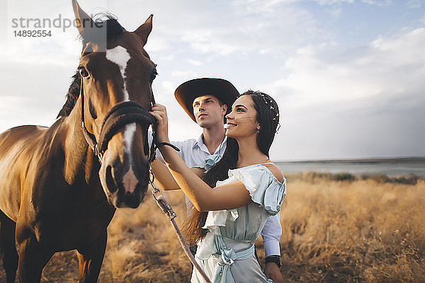 Junges Paar mit Pferd auf einem Feld