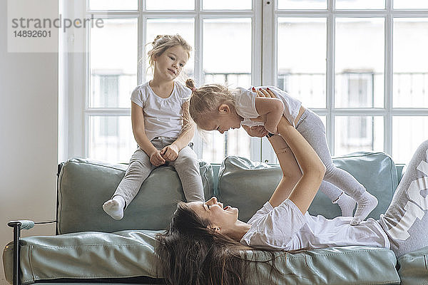 Mutter spielt mit ihren Töchtern auf dem Sofa