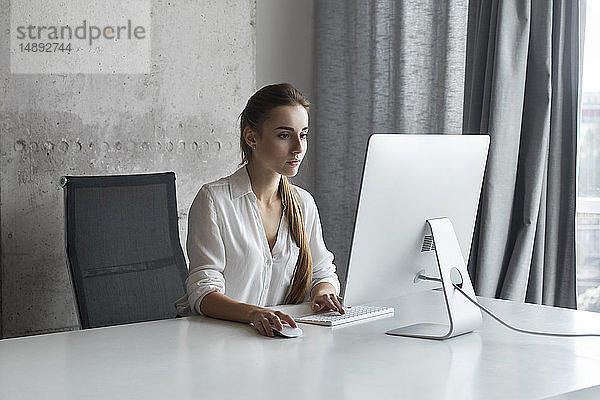 Junge Geschäftsfrau arbeitet an einem Desktop-Computer