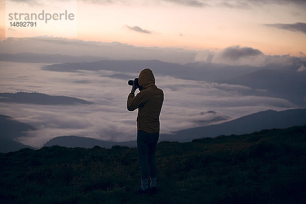 Silhouette eines jungen Mannes  der bei Sonnenuntergang im Karpatengebirge fotografiert