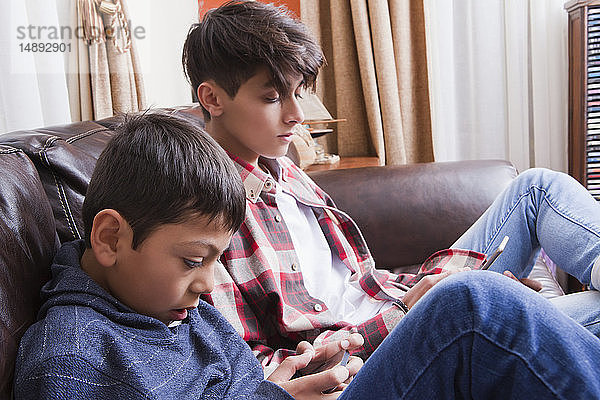 Brüder benutzen Smartphones auf dem Sofa