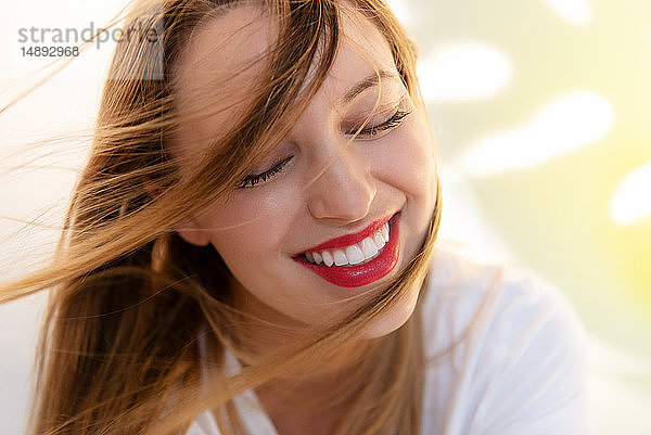 Porträt einer windgepeitschten jungen Frau mit rotem Lippenstift