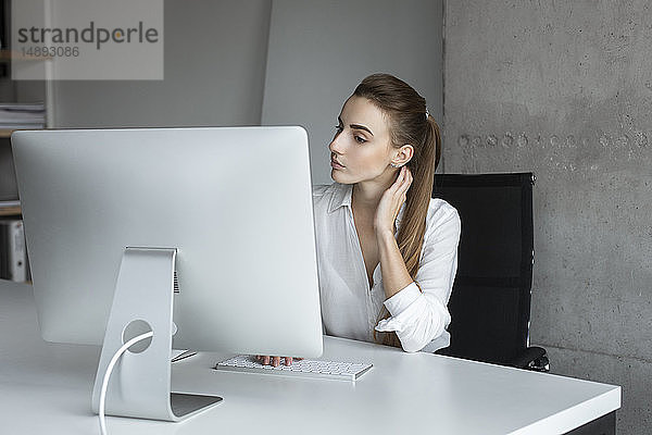 Junge Geschäftsfrau bei der Arbeit an einem Desktop-Computer