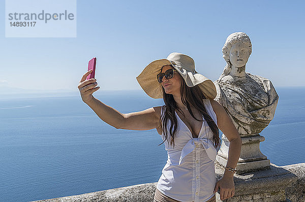 Frau macht Selfie bei Skulptur-Büste