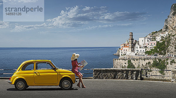 Frau mit Landkarte an gelbes Auto gelehnt in Atrani  Italien