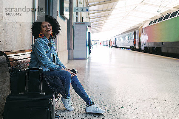 Junge Frau mit Smartphone auf dem Bahnsteig