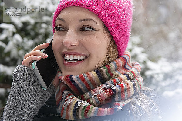Junge Frau beim Telefonieren im Schnee