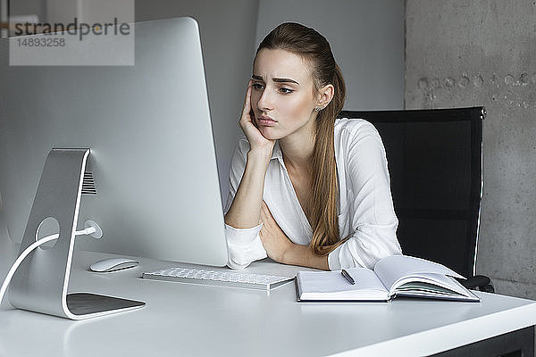 Depressive Geschäftsfrau  die an einem Desktop-Computer arbeitet