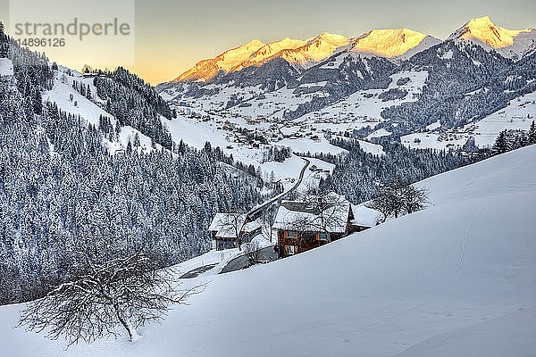 Österreich  Biosphärenpark Großes Walsertal  Dorf Raggal und das verschneite Tal vom Weiler Marul aus  bei Sonnenaufgang; bg. die Gipfel von rechts: Kreuzspitz (1947 m)  Melkspitze (1935 m)  Talispitz (2000 m)  Kuhspitz (1963 m)'