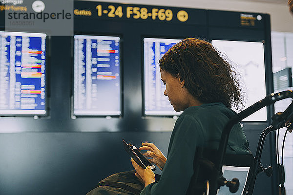 Seitenansicht einer Geschäftsfrau  die am Flughafen am Telefon sitzt