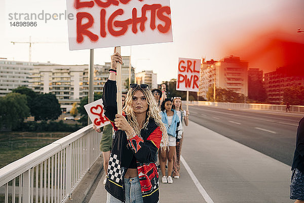 Frauen mit Plakaten marschieren für Gleichberechtigung gegen den Himmel in der Stadt