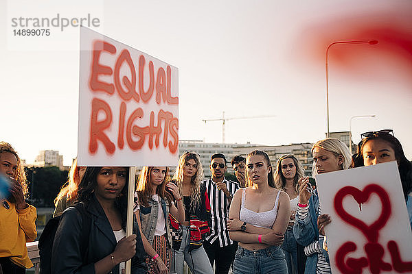 Frauen und Männer mit Plakaten  die für gleiche Rechte gegen den Himmel in der Stadt protestieren