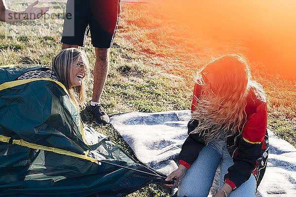 Spielerische Freunde genießen es  während sie bei einer Veranstaltung Zelt und Rasen machen