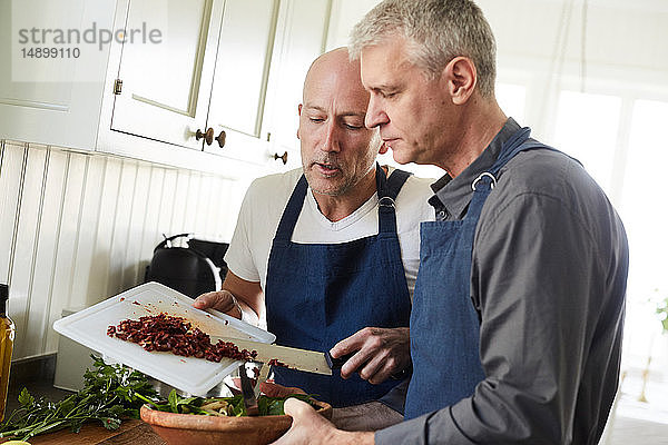 Kahler  reifer Mann hilft Freund beim Kochen zu Hause