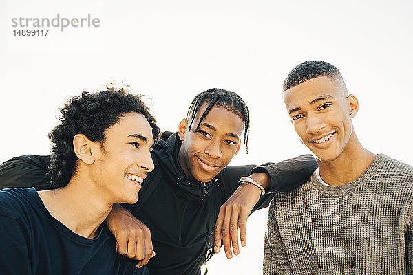 Porträt von lächelnden Teenager-Jungen mit Freund vor klarem Himmel